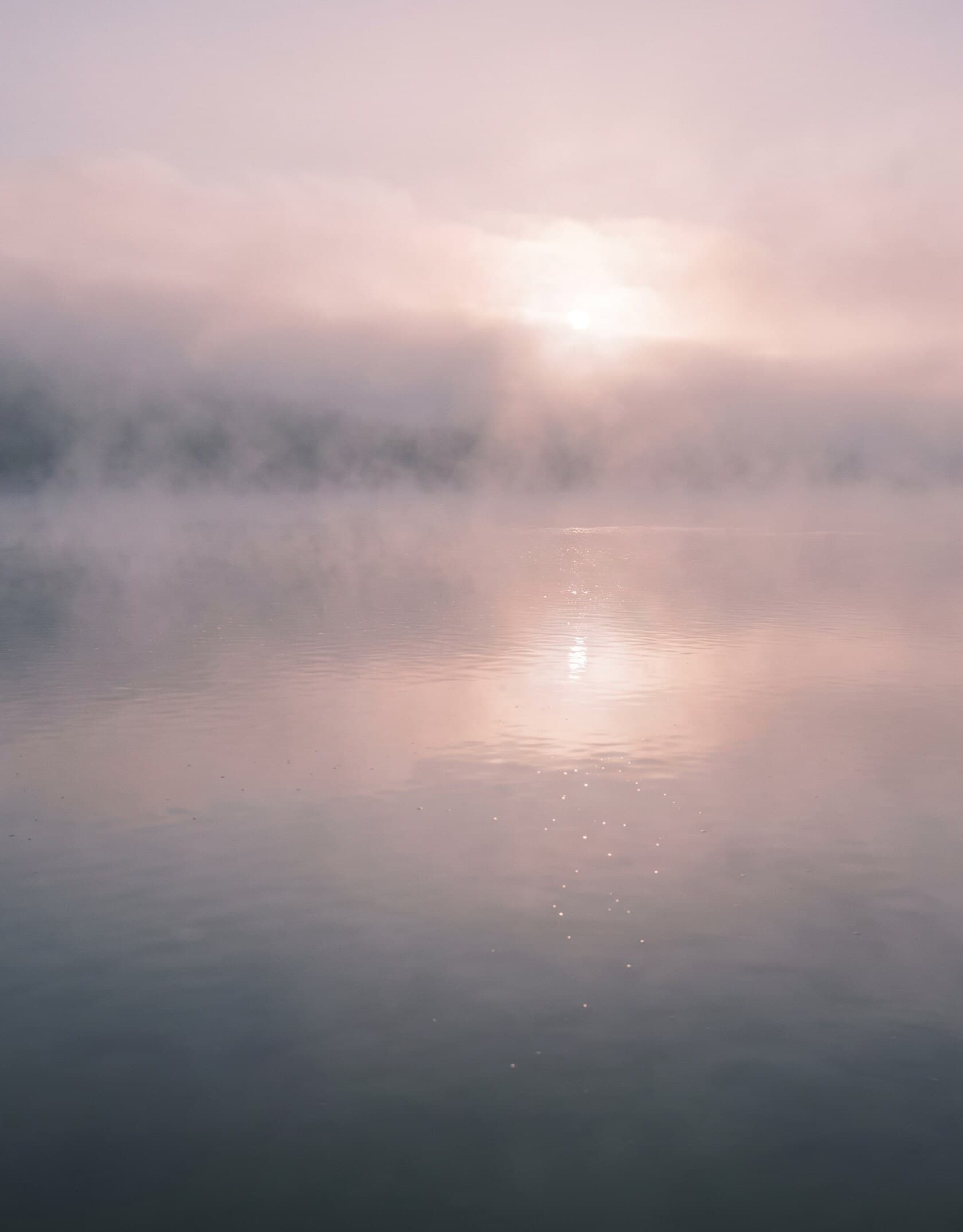 Dunst über einer ruhigen Wasserfläche im ersten Morgenlicht